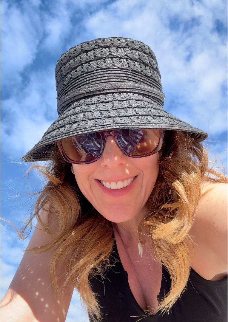 Jill at the beach wearing a black hat